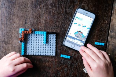 Riga, Letonya - 26 Aralık 2020: Lego ile oynayan çocuk, plastik inşaat oyuncakları ve talimatlar için akıllı telefonu kullanıyor. Seçici odak