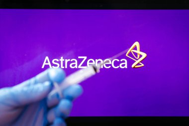 AstraZeneca Covid-19 aşı konsepti. Şırınganın yakın çekimi ve arka planda AstraZeneca şirketinin logosu. Dikkati dağılmış. Yüksek kalite fotoğraf