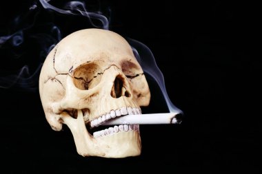 Kafatası ve yanan sigara. Sigara konsepti yüzünden ölüm. Odaklanmamış