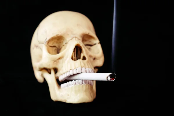 Skull and burning cigarette. Death from smoking concept. Selective focus