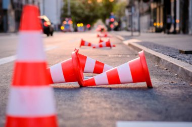 Bright orange traffic cones standing in a row on dark asphalt in the city. Road works. Selective focus