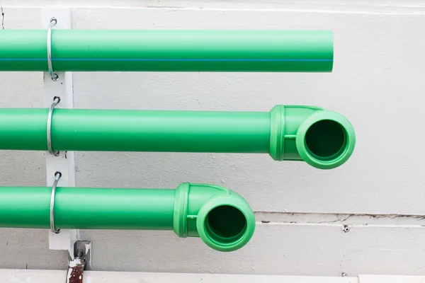 Green pipes on cement wall — Stock Photo, Image