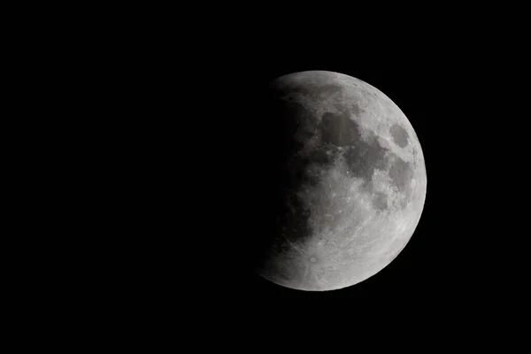 The moon during a lunar eclipse. About one third of the moon is in the shadow of the earth. There is room for text.