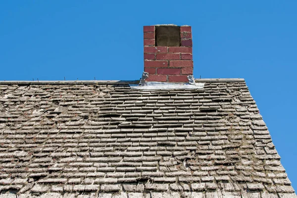 貧しい修理では非常に古い木の帯状の屋根 煙突が屋根の上にある 屋根から苔や地衣類が成長しています 上の空は青い — ストック写真