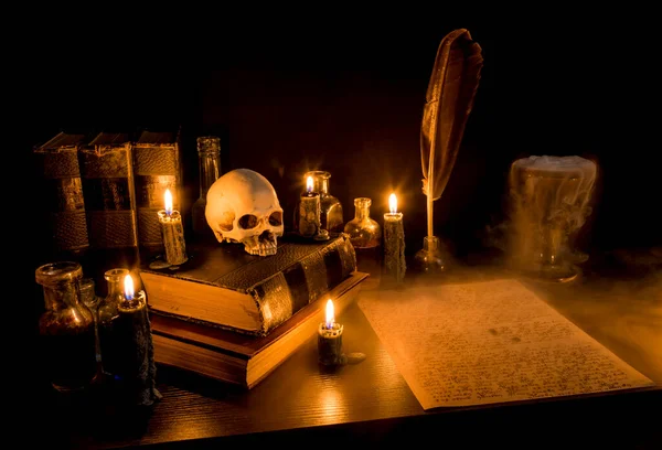 마법사의 책상이야 책상에 촛불을 사람의 두개골 물병등이 안개가고 렛에서 양피지로 — 스톡 사진
