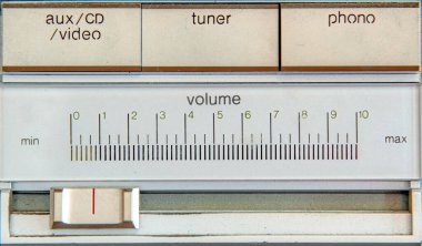 Eski bir müzik setinin bazı kontrollerini kapatıyorum. Ses kaydıracı giriş kontrollerinin altında. Metin fırçalanmış metalde..
