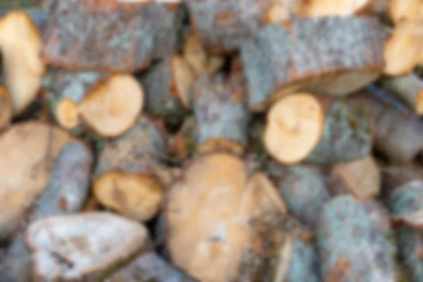 Background blur of a pile of cut wood and logs. Many pieces of different sizes.