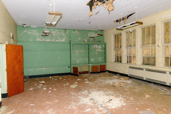 An empty room in an old abandoned school. Ceiling falling and debris on floor. This room was the library.