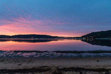 Gündoğumu ve yansımaları, Avustralya, NSW 'deki Woy Woy rıhtımında yüksek bulutlu bir su manzarası..