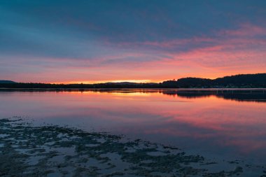 Gündoğumu ve yansımaları, Avustralya, NSW 'deki Woy Woy rıhtımında yüksek bulutlu bir su manzarası..