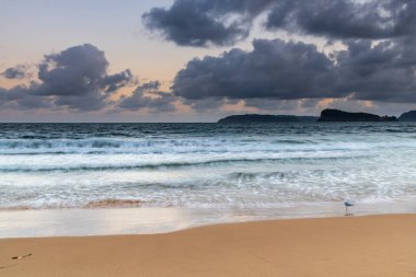Günbatımı deniz manzarası ve Ocean Beach 'te bulutlu bir gökyüzü Merkezi Sahilde Umina Sahili, NSW, Avustralya.