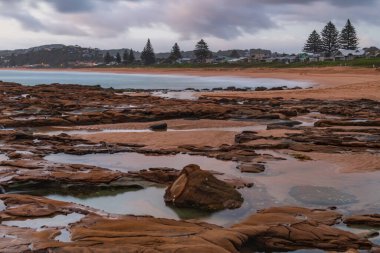 Bulutlu gündoğumu deniz manzarası ve Kuzey Avoca Sahili 'nde tesselleştirilmiş kaya platformu, NSW, Avustralya.