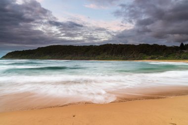 Central Coast, NSW, Avustralya 'daki Bateau Körfezi' nde bulutlar ve yağmurlu bir plaj gündoğumu.