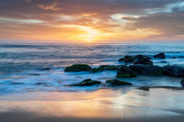 Deniz üzerindeki yüksek bulutlar, Orta Sahildeki Killcare Sahili 'nden mavi, pembe ve turuncu gündoğumu, NSW, Avustralya.