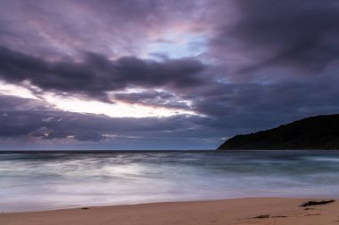 Central Coast, NSW, Avustralya 'daki Bateau Körfezi' nde bulutlar ve yağmurlu bir plaj gündoğumu.