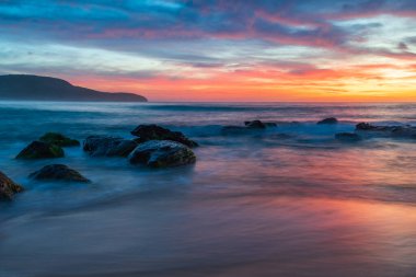 Deniz üzerindeki yüksek bulutlar, Orta Sahildeki Killcare Sahili 'nden mavi, pembe ve turuncu gündoğumu, NSW, Avustralya.