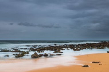 Central Coast, NSW, Avustralya 'daki MacMasters Sahili' nde bulutlu bir gün doğumu..