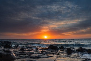 Central Coast, NSW, Avustralya 'daki North Avoca Sahili' nde yüksek bulutlu ve tesselleştirilmiş kaya platformu ile renkli gündoğumu deniz manzarası.