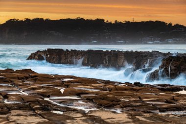 Central Coast, NSW, Avustralya 'daki North Avoca Sahili' nde yüksek bulutlu ve tesselleştirilmiş kaya platformu ile renkli gündoğumu deniz manzarası.