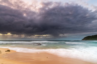 Central Coast, NSW, Avustralya 'daki Bateau Körfezi' nde bulutlar ve yağmurlu bir plaj gündoğumu.