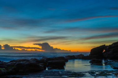 Ufuktaki bir bulut kümesi üzerinde yüksek bulutlar sürükleniyor. Central Coast, NSW, Avustralya 'daki Killcare Sahili' nden gündoğumu deniz manzarası..