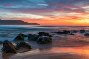 Deniz üzerindeki yüksek bulutlar, Orta Sahildeki Killcare Sahili 'nden mavi, pembe ve turuncu gündoğumu, NSW, Avustralya.