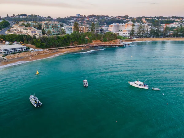 Central Coast, NSW, Avustralya 'daki Terrigal kıyı banliyösüne bakan teknelerle hafif bulutlu gün doğumu deniz manzarası..