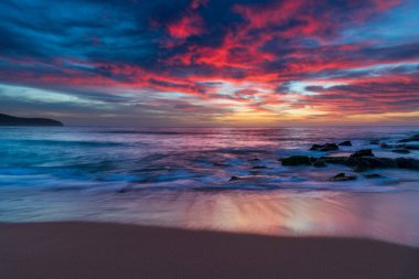 Deniz üzerindeki yüksek bulutlar, Orta Sahildeki Killcare Sahili 'nden mavi, pembe ve turuncu gündoğumu, NSW, Avustralya.