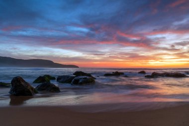 Deniz üzerindeki yüksek bulutlar, Orta Sahildeki Killcare Sahili 'nden mavi, pembe ve turuncu gündoğumu, NSW, Avustralya.