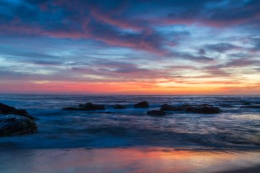 Deniz üzerindeki yüksek bulutlar, Orta Sahildeki Killcare Sahili 'nden mavi, pembe ve turuncu gündoğumu, NSW, Avustralya.