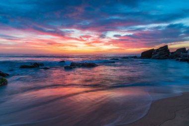 Deniz üzerindeki yüksek bulutlar, Orta Sahildeki Killcare Sahili 'nden mavi, pembe ve turuncu gündoğumu, NSW, Avustralya.
