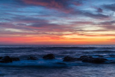 Deniz üzerindeki yüksek bulutlar, Orta Sahildeki Killcare Sahili 'nden mavi, pembe ve turuncu gündoğumu, NSW, Avustralya.