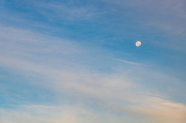Alacakaranlık, yüksek bulutlar ve mavi gökyüzündeki ay.