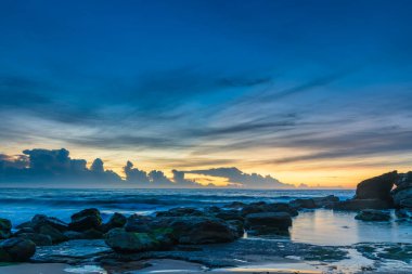 Ufuktaki bir bulut kümesi üzerinde yüksek bulutlar sürükleniyor. Central Coast, NSW, Avustralya 'daki Killcare Sahili' nden gündoğumu deniz manzarası..