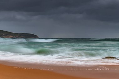Yağmur bulutları gökyüzünü dolduruyor ve dalgalar hızla yükseliyor. Central Coast, NSW, Avustralya 'daki Killcare Sahili' nden gündoğumu deniz manzarası..