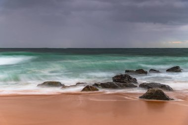 Yağmur bulutları gökyüzünü dolduruyor ve dalgalar hızla yükseliyor. Central Coast, NSW, Avustralya 'daki Killcare Sahili' nden gündoğumu deniz manzarası..
