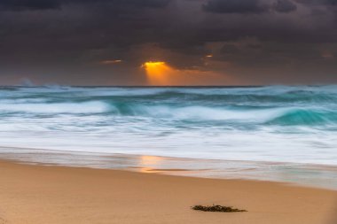 Avustralya, NSW 'nin merkez kıyısındaki Birdie Plajı' ndan deniz kenarında bulutlu bir güneş doğuyor..