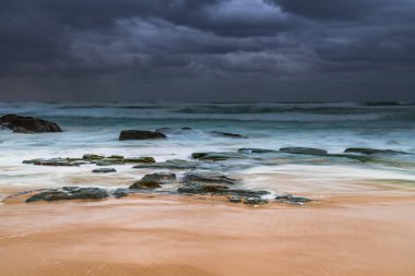 Avustralya, NSW 'nin merkez kıyısındaki Birdie Plajı' ndan deniz kenarında bulutlu bir güneş doğuyor..