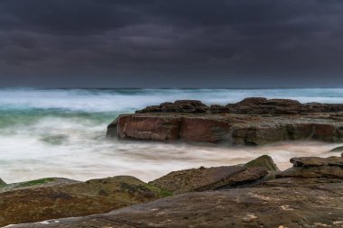 Avustralya, NSW 'nin merkez kıyısındaki Birdie Plajı' ndan deniz kenarında bulutlu bir güneş doğuyor..
