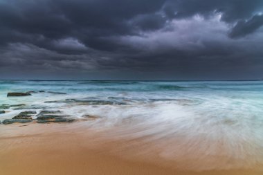 Avustralya, NSW 'nin merkez kıyısındaki Birdie Plajı' ndan deniz kenarında bulutlu bir güneş doğuyor..