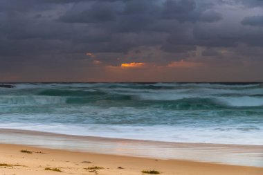 Avustralya, NSW 'nin merkez kıyısındaki Birdie Plajı' ndan deniz kenarında bulutlu bir güneş doğuyor..