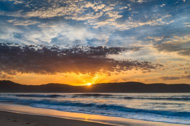 Gündoğumu renkleriyle kumsalda geçen sonbahar günleri Umina Sahili 'nde, NSW, Avustralya.