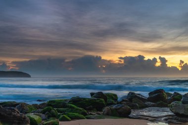 Ufuktaki bir bulut kümesi üzerinde yüksek bulutlar sürükleniyor. Central Coast, NSW, Avustralya 'daki Killcare Sahili' nden gündoğumu deniz manzarası..