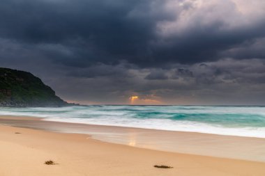 Avustralya, NSW 'nin merkez kıyısındaki Birdie Plajı' ndan deniz kenarında bulutlu bir güneş doğuyor..