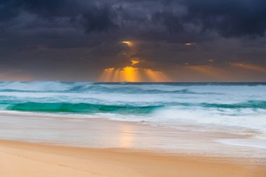 Avustralya, NSW 'nin merkez kıyısındaki Birdie Plajı' ndan deniz kenarında bulutlu bir güneş doğuyor..