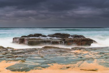Avustralya, NSW 'nin merkez kıyısındaki Birdie Plajı' ndan deniz kenarında bulutlu bir güneş doğuyor..