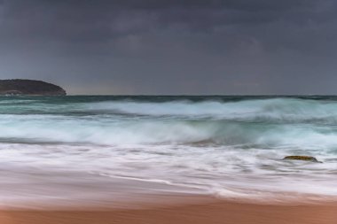 Yağmur bulutları gökyüzünü dolduruyor ve dalgalar hızla yükseliyor. Central Coast, NSW, Avustralya 'daki Killcare Sahili' nden gündoğumu deniz manzarası..