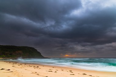 Avustralya, NSW 'nin merkez kıyısındaki Birdie Plajı' ndan deniz kenarında bulutlu bir güneş doğuyor..