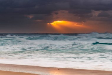 Avustralya, NSW 'nin merkez kıyısındaki Birdie Plajı' ndan deniz kenarında bulutlu bir güneş doğuyor..
