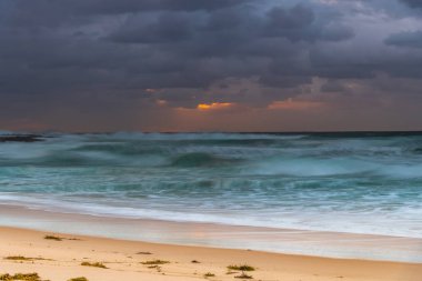 Avustralya, NSW 'nin merkez kıyısındaki Birdie Plajı' ndan deniz kenarında bulutlu bir güneş doğuyor..
